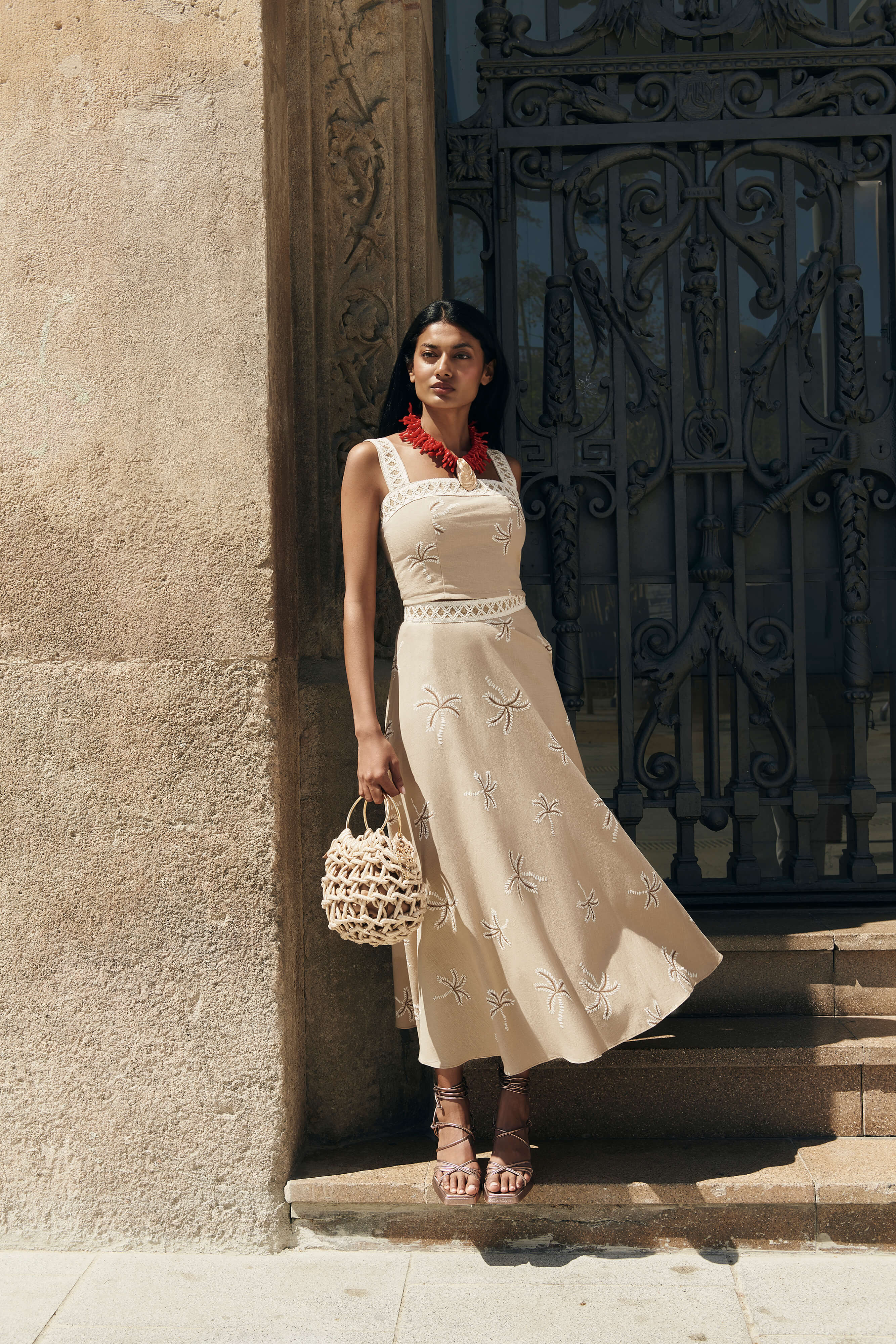 Falda Palmar midi con vuelo y nesgas, estampado de palmeras beige. Cinta decorativa en la cadera y cremallera trasera