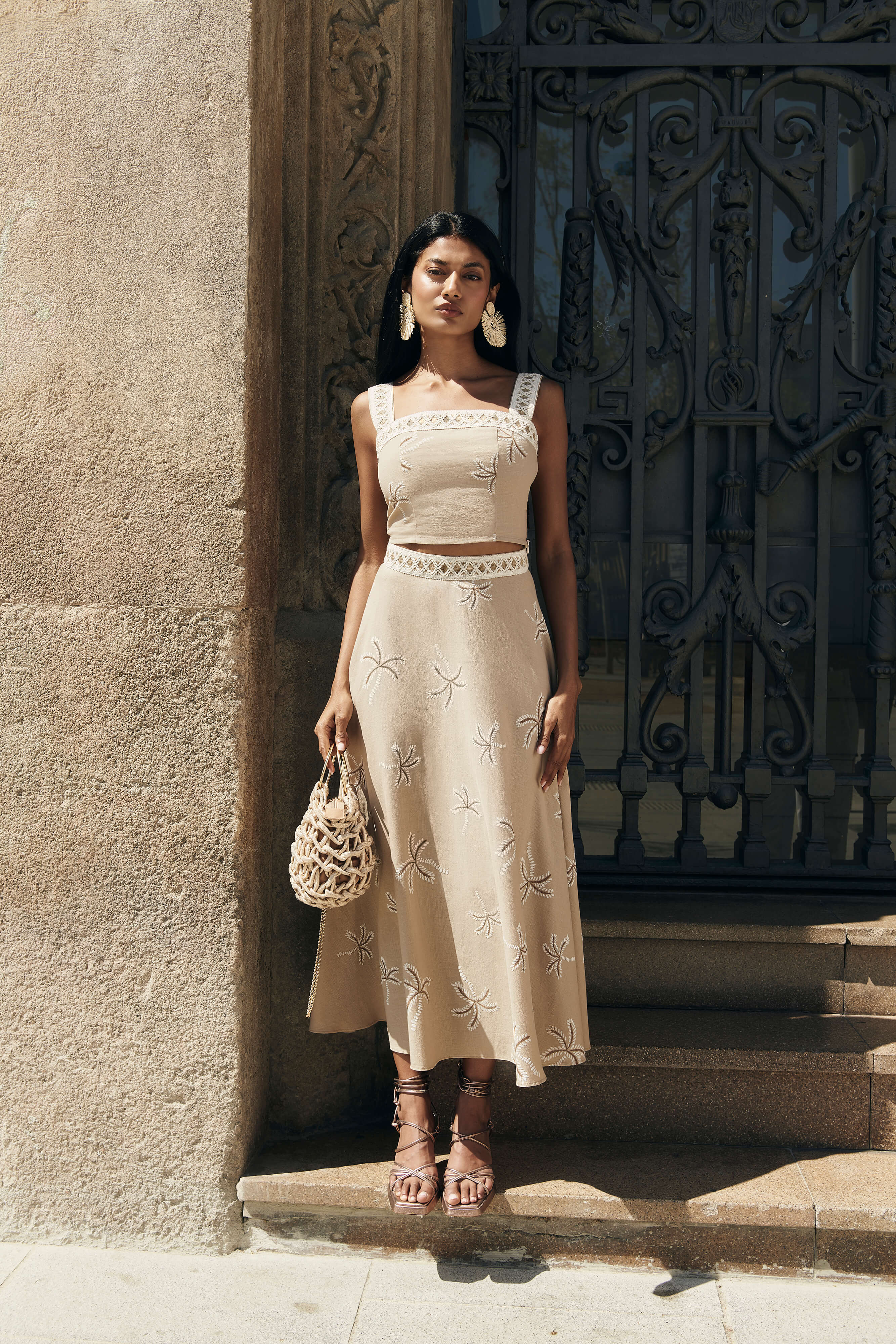 Falda Palmar midi con vuelo y nesgas, estampado de palmeras beige. Cinta decorativa en la cadera y cremallera trasera