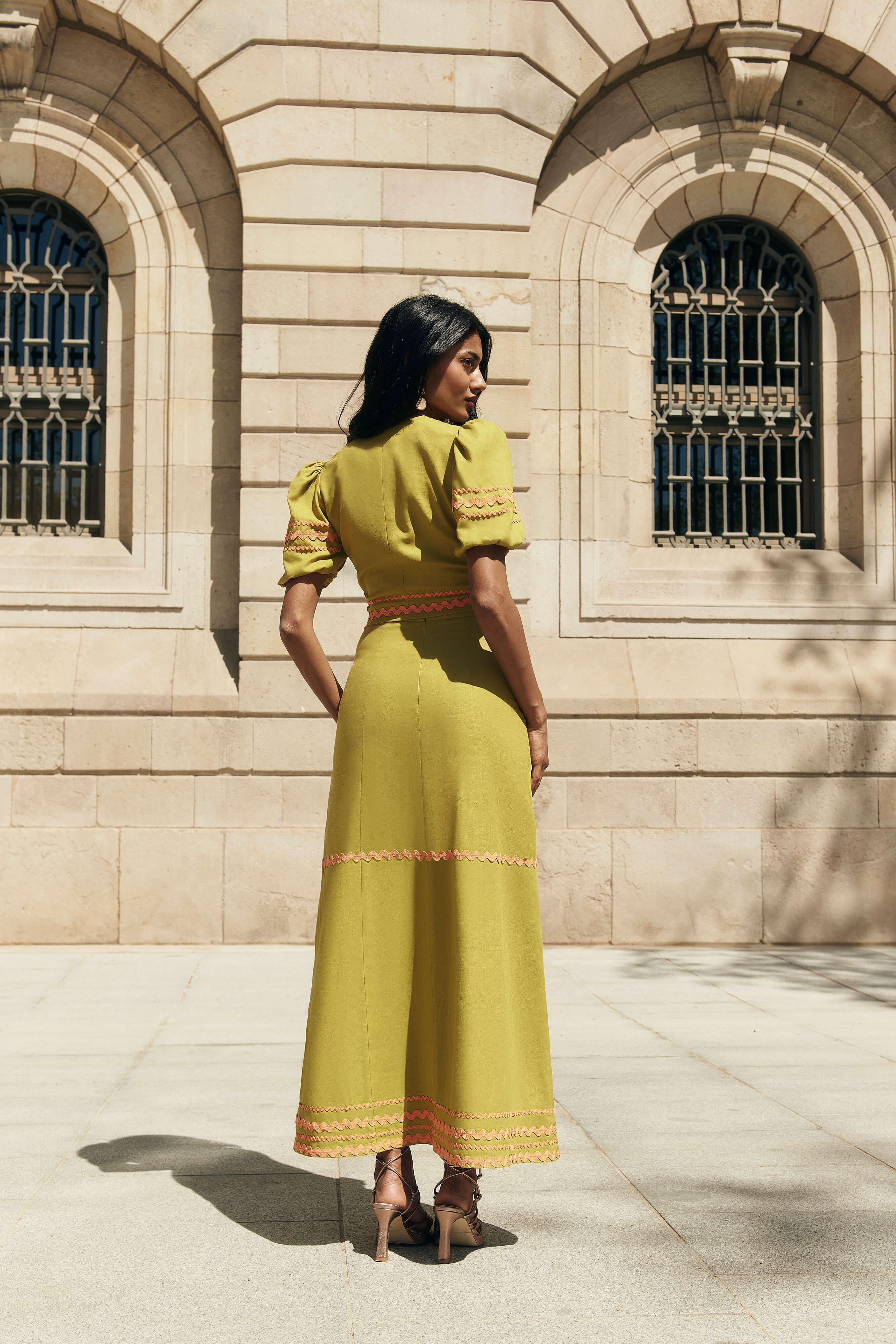 Falda Sabina en Verde oliva de lino y viscosa con corte midi, cintas decorativas naranjas y cremallera trasera.