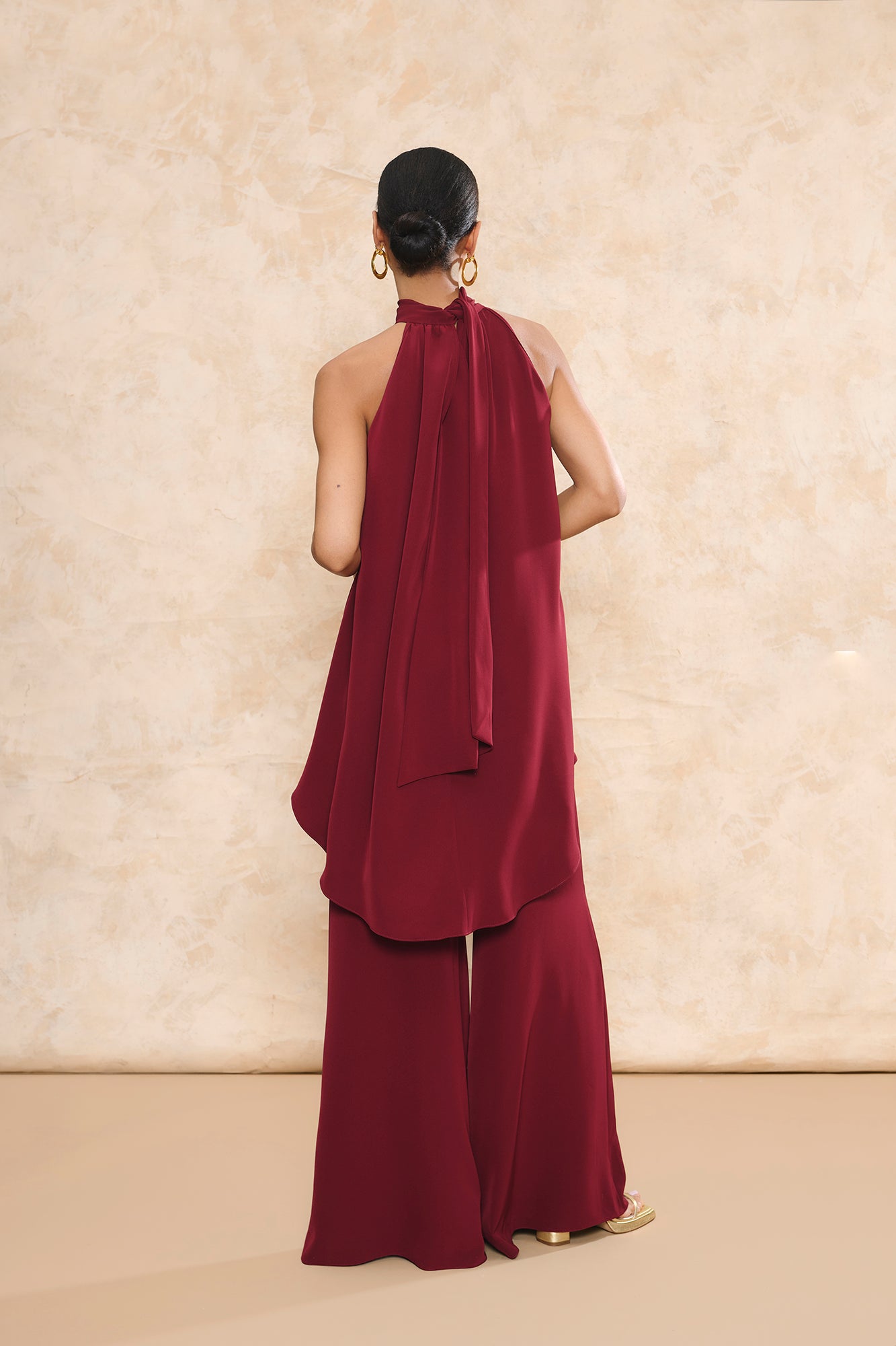 Conjunto Triana granate de pantalón de invitada palazzo y top halter asimétrico con caída fluida de Miphai.