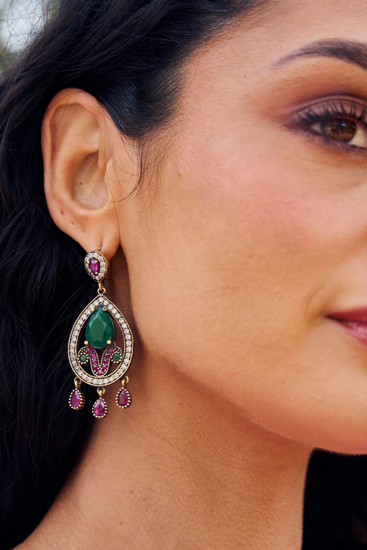Pendientes Sole de 5,5 cm con diseño en lágrima, piedras en tonos esmeralda y buganvilla, circonitas brillantes y cierre de click.