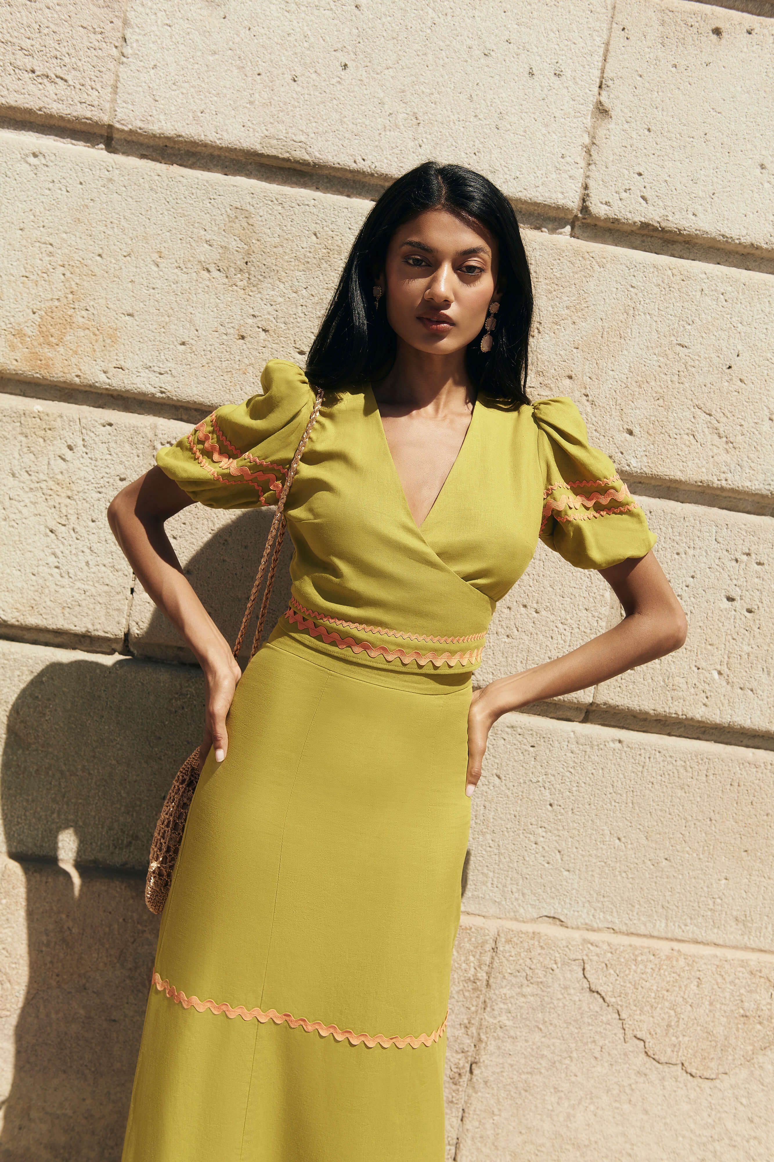 Top cruzado en lino verde oliva con botones laterales, mangas abullonadas y cintas naranjas.