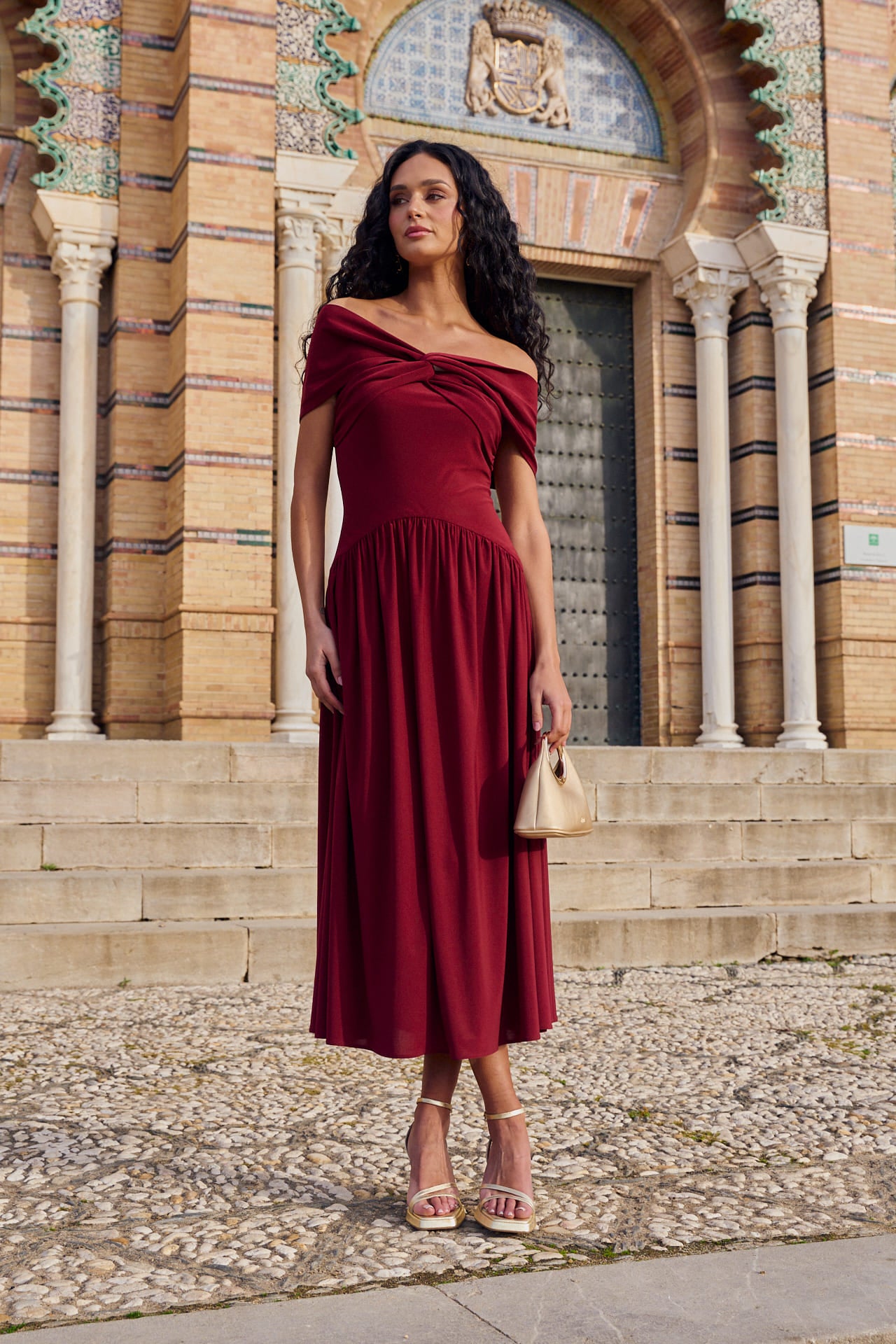 Vestido Cayetana Midi en punto de seda granate, con escote palabra de honor y corte asimétrico.