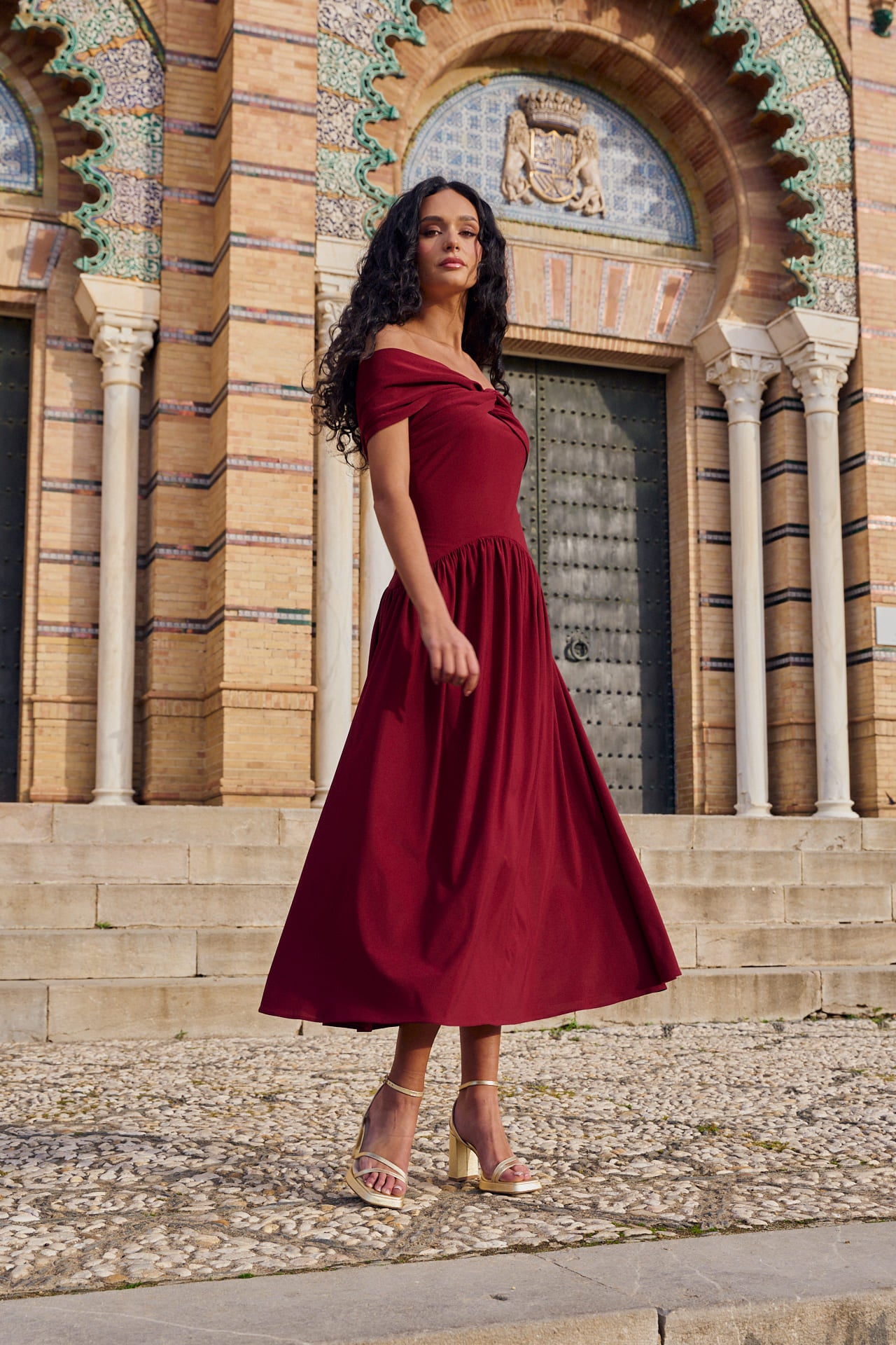 Vestido Cayetana Midi en punto de seda granate, con escote palabra de honor y corte asimétrico.