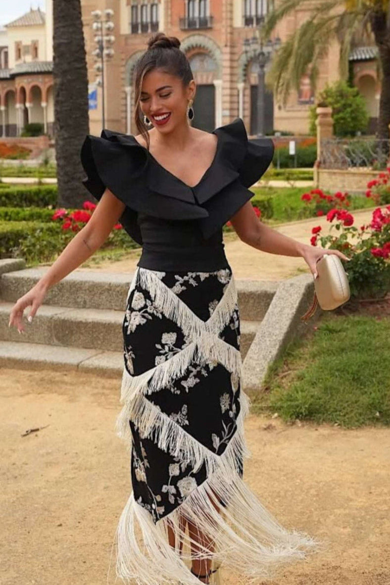 La falda Adela Negro es una falda midi de viscosa con bordado floral marfil y flecos en tres tamaños que forman un diseño en zigzag hasta el bajo.