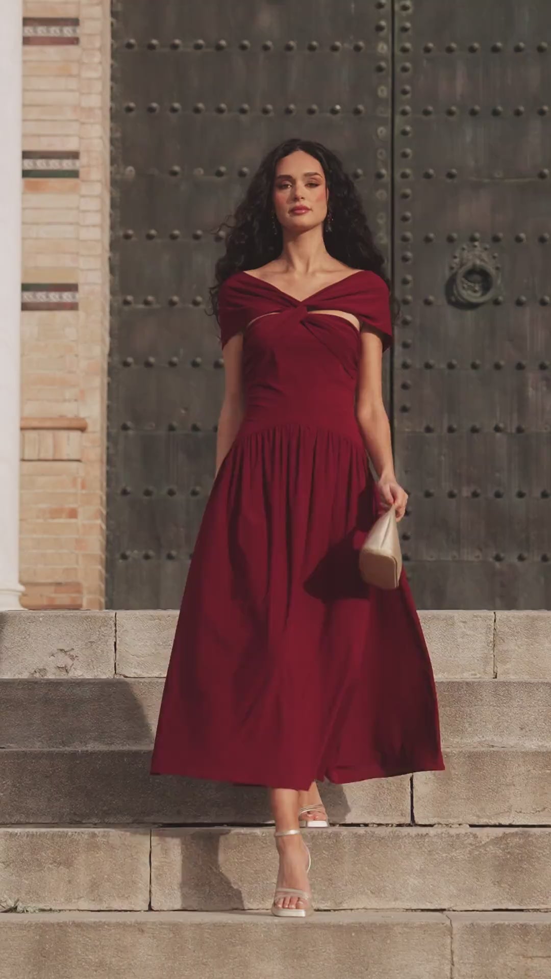 Vestido Cayetana Midi en punto de seda granate, con escote palabra de honor y corte asimétrico.