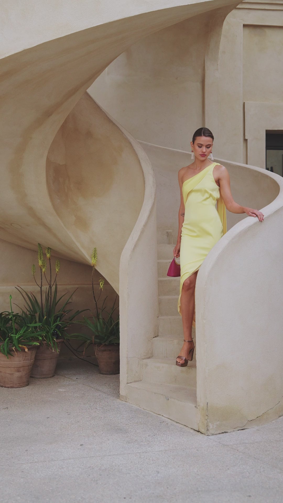 Vestido largo Lotus en crepé satén amarillo, con escote asimétrico, capa y espalda con tiras cruzadas.